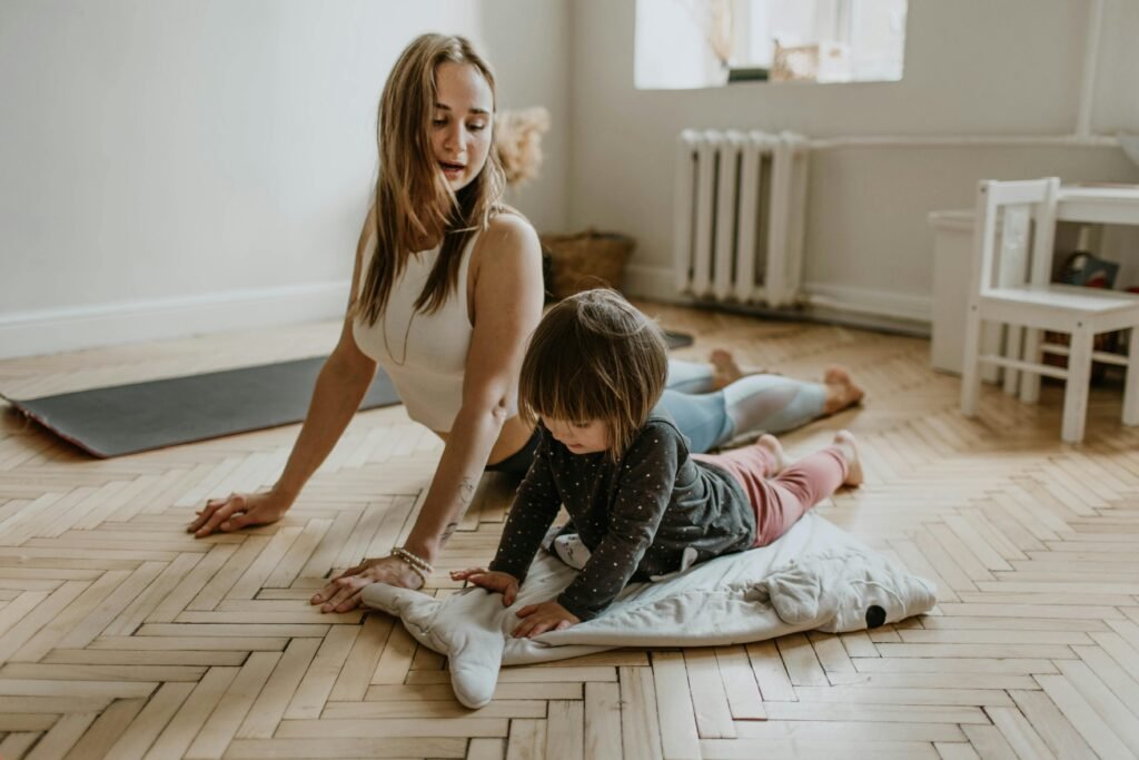 pexels-photo-3094230-3094230 A mother and child practicing yoga together at home on a sunny day, fostering wellness and connection.
